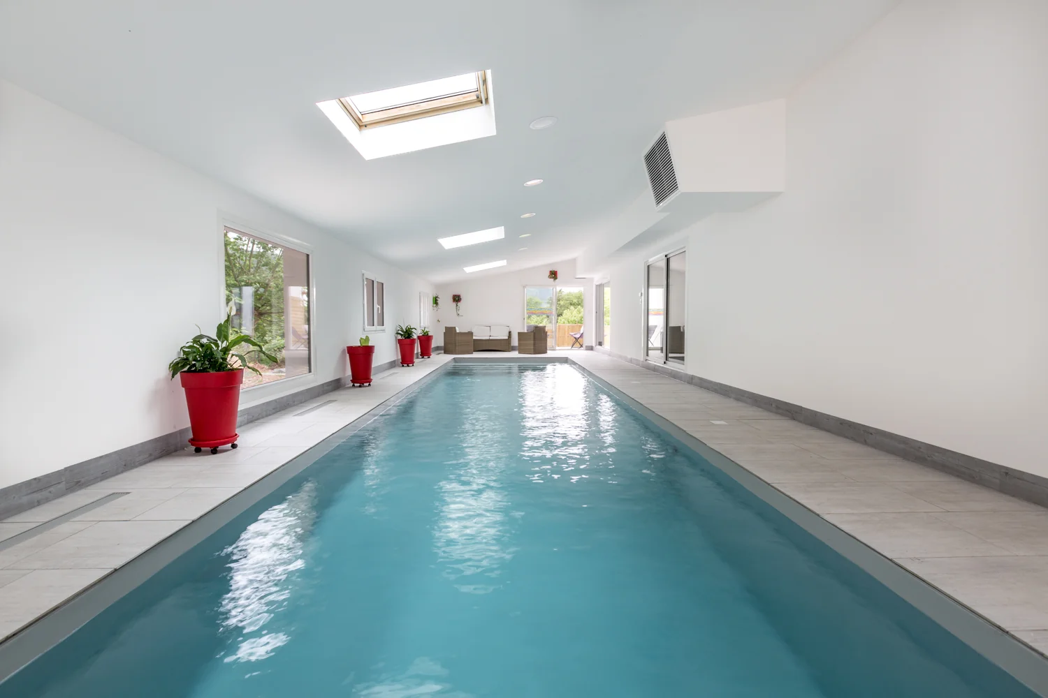 Piscine intérieure entourée de murs clairs et de fenêtres