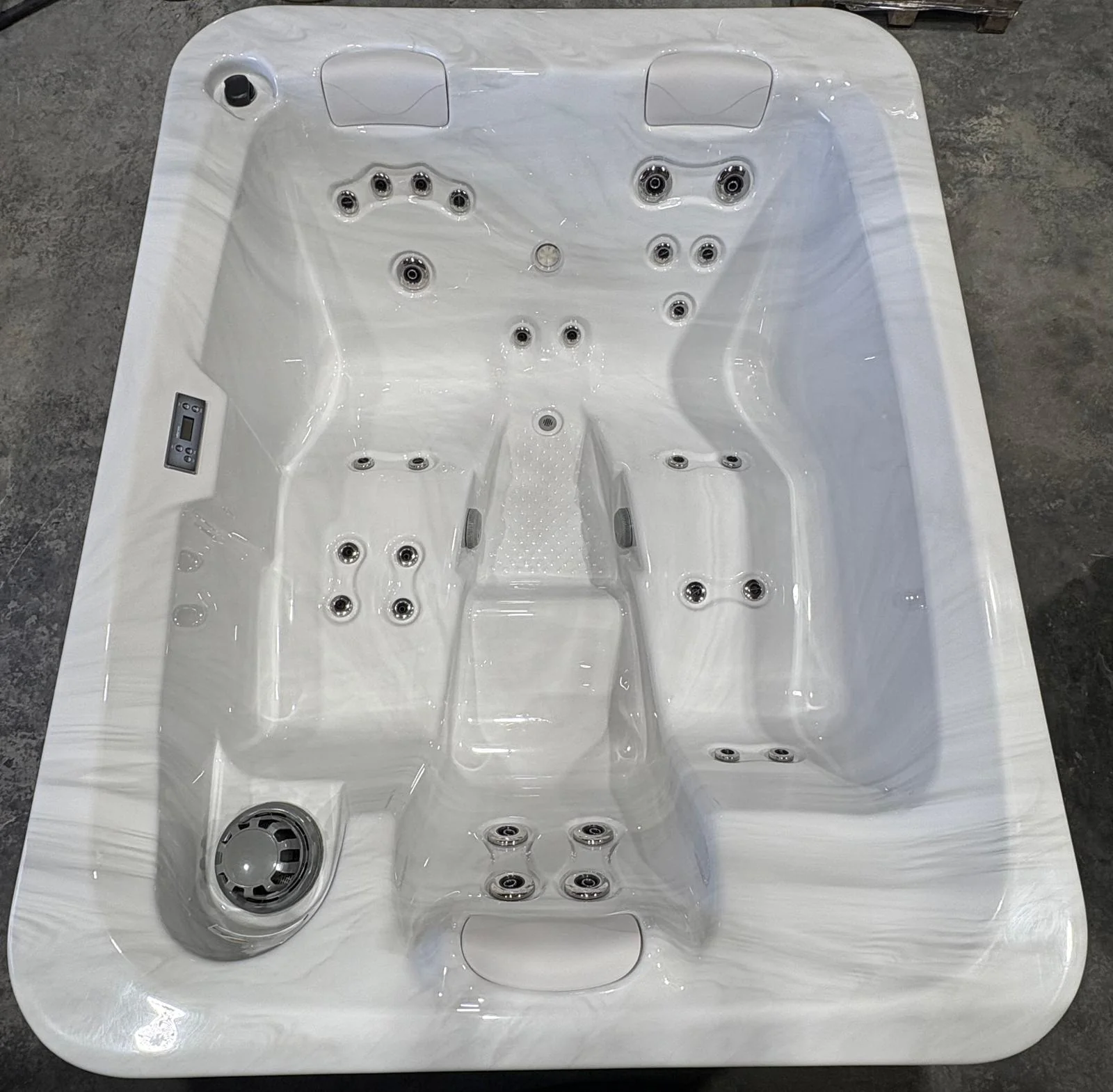 Spa blanc avec assises moulées et buses de massage, photographié de dessus